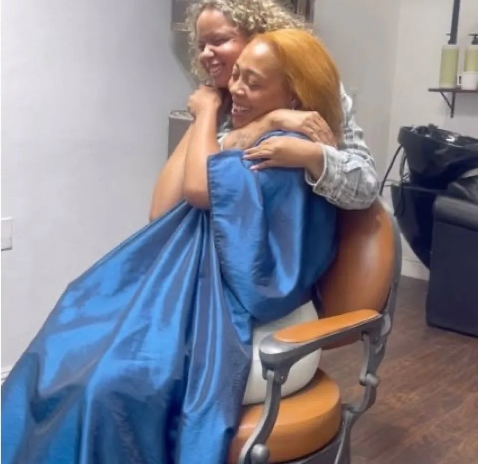 Tycetycehair laughing with a client wrapped in a blue cutting cape.