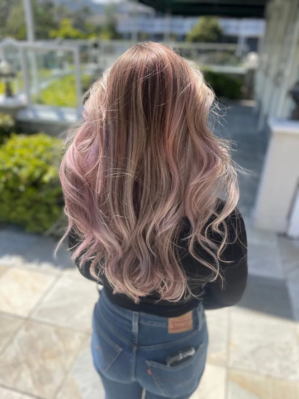 Soft rose-pink balayage on long wavy hair.