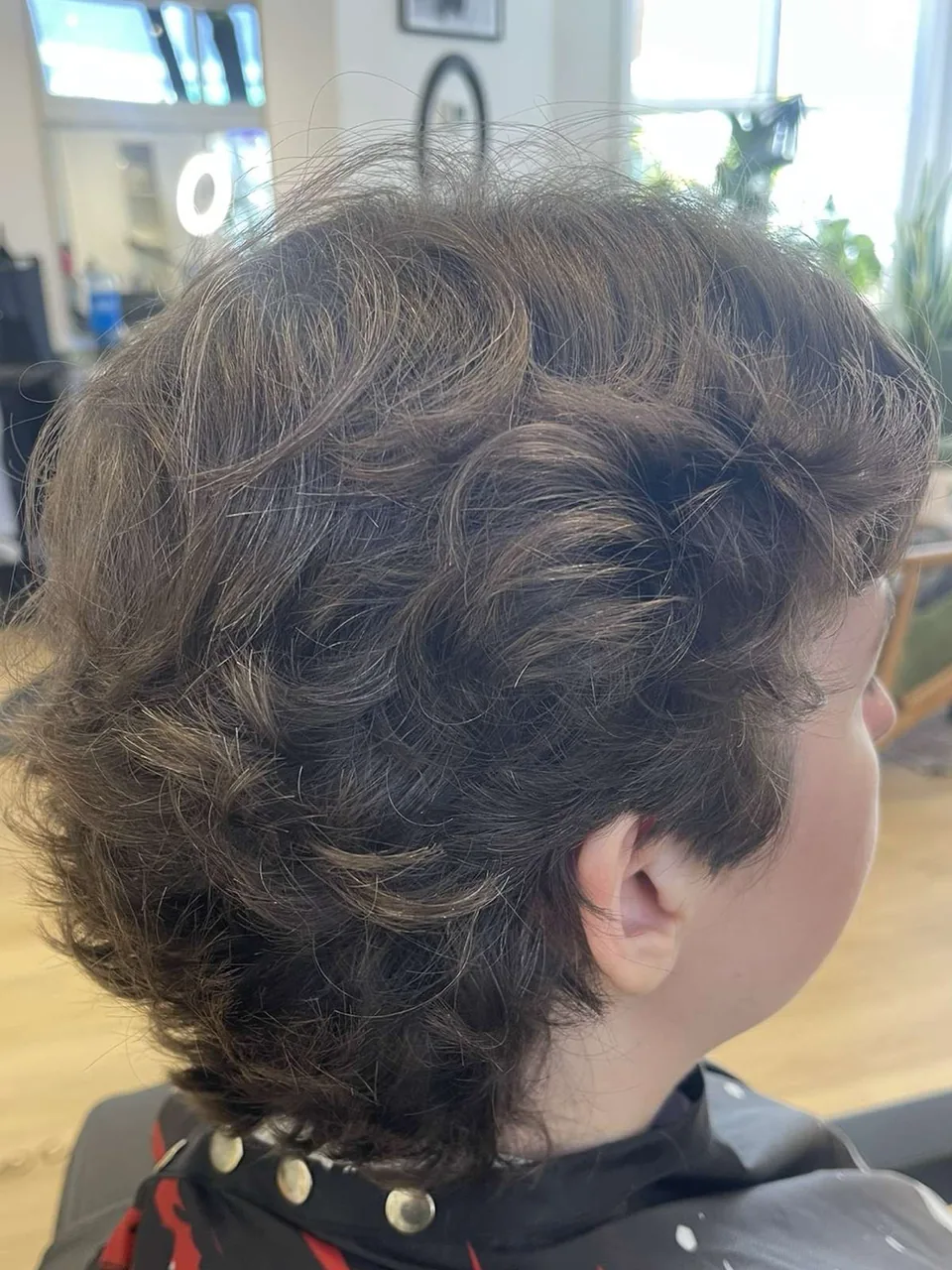 A wavy mullet, short and textured through the sides with a longer nape.